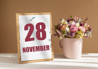 november 28. 28th day of month, calendar date.Bouquet of dead wood in pink mug on desktop.Cork board with calendar sheet on white-beige background. Concept of day of year, time planner, autumn month