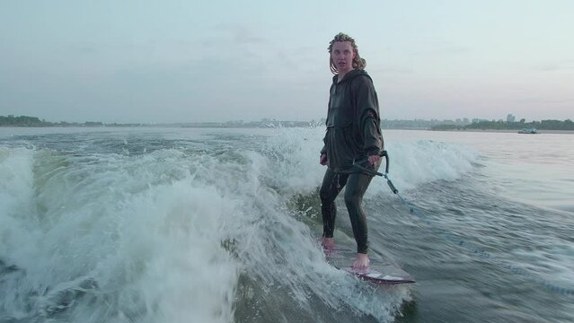 A female surfer jumping on a wakeboard. An experienced wakeboarder splashes water drops into the camera.