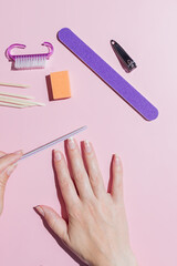 Woman aligns her nails with a nail file. Alignment of the nail edge. Manicure at home for yourself. A woman's hand with healthy natural nails. procedure of nail care. Top view.
