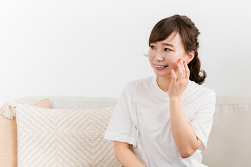 Fototapeta premium ソファに座りながら肌を触る女性（スキンケア） 