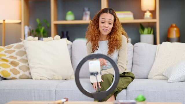 Influencer recording a video on a phone at home. Young woman live streaming a broadcast online with a ring light for a vlog channel. Filming a fun podcast while speaking to followers on social media