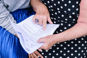 Hands of mother pointing on letter with daughter sitting at park