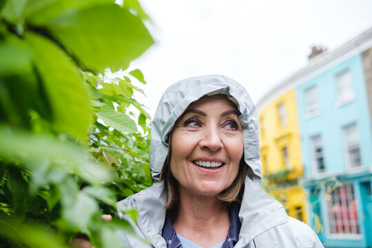 Smiling Senior Woman Wearing Windbreaker By Plants