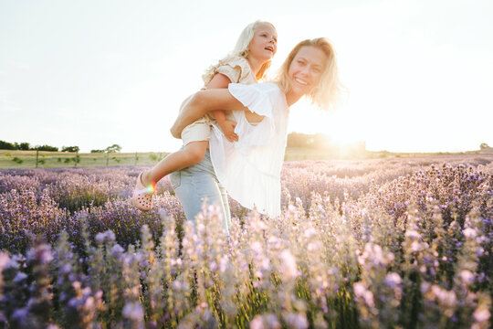 Happy mother giving piggyback ride to daughter in field