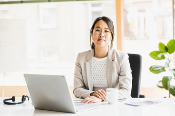 Smiling businesswoman sitting at desk in office