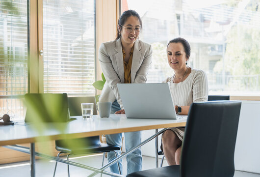 Happy businesswoman discussing work with colleague at work place
