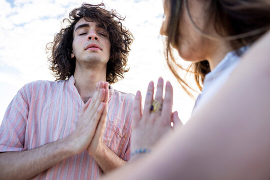 Young couple meditating with hands clasped