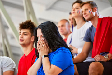 Woman with hands covering mouth expressing disappointment at sports event in stadium