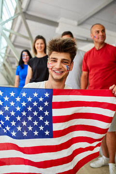 Smiling young man holding American Flag at sports event in stadium