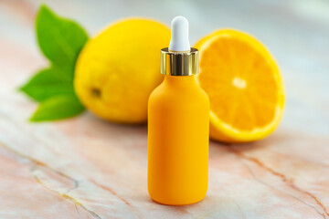 Serum in a cosmetic bottle next to an orange. Natural cosmetics and face care.