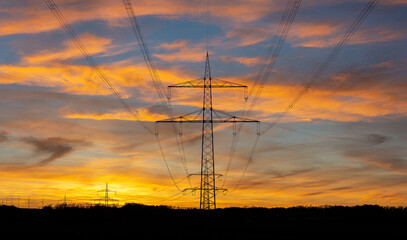 Power grid high voltage pylons in evening red with blue sky. Power supply, power distribution, power transmission, power transmission, high voltage power supply.