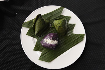 sticky rice cake with grated coconut inside and cover by banana leaf 