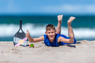 Young boy playing tennis on beach. Kids sport concept. Horizontal sport theme poster, greeting cards, headers, website and app