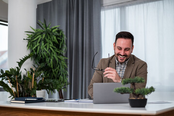 Smiling professional analyzing plan on laptop while working at office