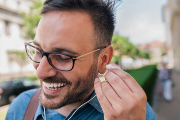 Close-up of cheerful businessman wearing headphones while standing on sidewalk