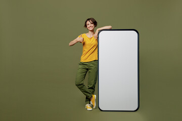 Full body young happy woman she 20s wear yellow t-shirt near big huge blank screen mobile cell...