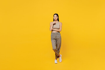 Fototapeta na wymiar Full body serious calm beautiful young latin woman 30s she wearing basic beige tank shirt look camera look aside on worksapce area mock up isolated on plain yellow backround People lifestyle concept.