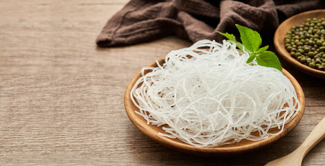 Asian vermicelli or cellophane noodle and mung green bean in wooden plate on wood table background. glass noodle                       - obrazy, fototapety, plakaty