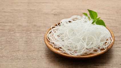 Asian vermicelli or cellophane noodle in wooden plate on wood table background. glass noodle                                                                              