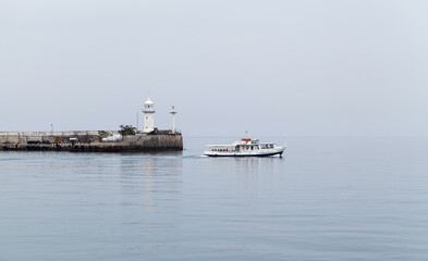 Fototapeta na wymiar Coastal view of Yalta. Small passenger ferry ship nd Lighthouse