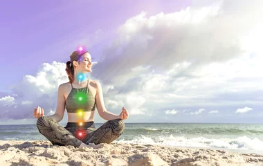 Deurstickers 7 chakras. Happy woman meditates on the seashore. Girl in lotus position © Alexa Joy