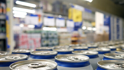 Fototapeta na wymiar Close-up of many white-blue cans of beer or another drink on a store shelf
