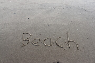 on the beach is carved with letters in the smooth sand the writing Beach