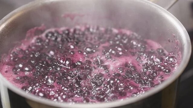 Preparing homemade blueberry jam in a saucepan.
