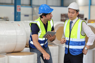 Architect or engineering man and worker sitting and checking large warehouse with computer. Multiethnic two business manager pointing and looking in future with warehouse building background.