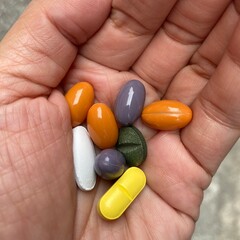 A palm holds various vitamins and minerals pills tablet. ready to take 