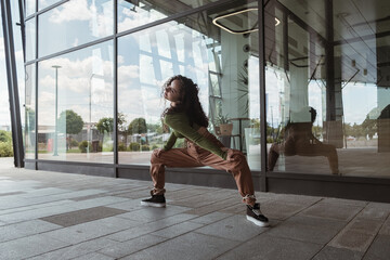 Female dancer stretching legs in front of the modern building