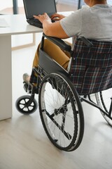 Obraz premium Freelancer in wheelchair using laptop near notebook and papers on table