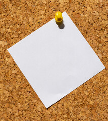 Yellow pinned note paper on a cork board