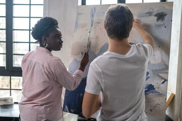 A tutor and a student near the easel looking positive