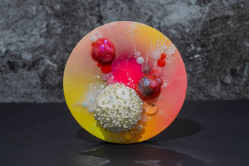 A pink and yellow round circle glitter blob art work of microcosmos pastel space microbes with...