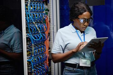 African female engineer setting up the work of computer system using digital tablet while standing...