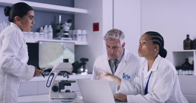 Team of scientists working on laptop in a medical research lab while creating a chemical formula for a vaccine. Diverse researchers brainstorming and discussing solutions to create and discover cure
