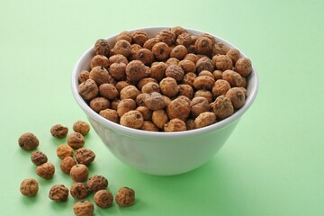 Chufa, tigernut, earth almond on ceramic bowl on green background. Healthy organic vegan food concept. Tiger nut for flour, milk, traditional typical homemade cold drink horchata from Valencia Spain