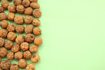 Top view of chufa, tigernut on green background with copy space for text. Tiger nut for flour, milk, oil, traditional typical homemade drink horchata from Valencia, Spain. Healthy vegan food concept. 