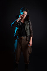 A cyberpunk character talks to someone over an ear implant. Futuristic concept, stylish guy on a black background in neon blue backlight