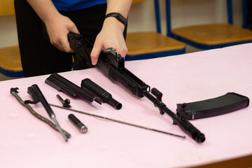 Assembling and disassembling a Kalashnikov assault rifle on a table. Details of the Kalashnikov assault rifle