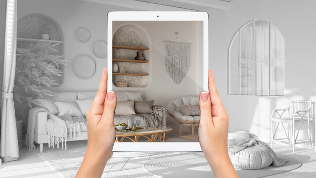 Hands holding tablet showing living room in boho style, total blank project background, augmented reality concept, application to simulate furniture and interior design products
