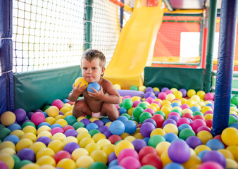 Boy in diaper with ball playing in playroom on weekend