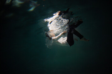 Sink. A young guy in a white shirt falls into the water, a photo from under the water. The concept...