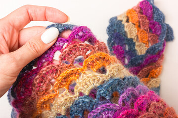 Knitted with colored woolen threads, an openwork item. Loops, pile, weave, edge and fold of material.