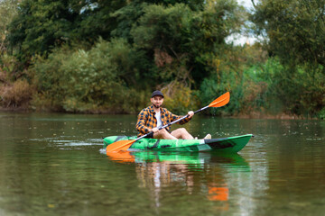 Smiling adult caucasian man kayaking at the river. The concept of the World Tourism Day and water sport