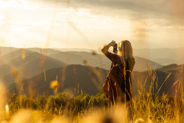 Beautiful woman sitting on mountain top and contemplating landscape.