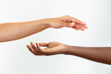 Hands with different skin colour, one african-american, one caucasian, touching each other on gary background.