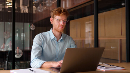 Young professional business man, freelancer, focused ethnic successful ceo, wearing glasses working on laptop, and studying using computer for online seminar webinar at office, coworking, library.