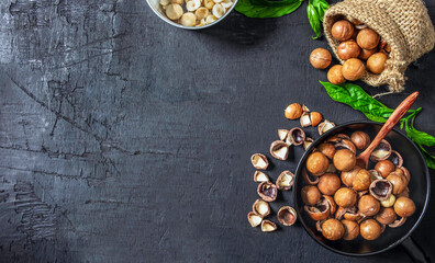 Fototapeta na wymiar Organic dry Macadamia nut in a brown sack on black wooden background